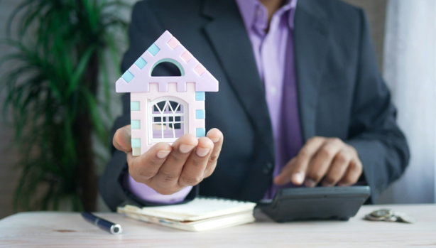 man-holding-model-house-at-desk-with-calculator.jpg man holding model house at desk with calculator